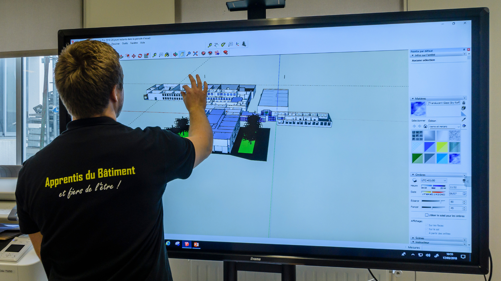 Un apprenant du BTS MEC (Management Économique de la Construction) travaille debout sur un écran tactile entrain de manipuler un plan numérique d'un bâtiment